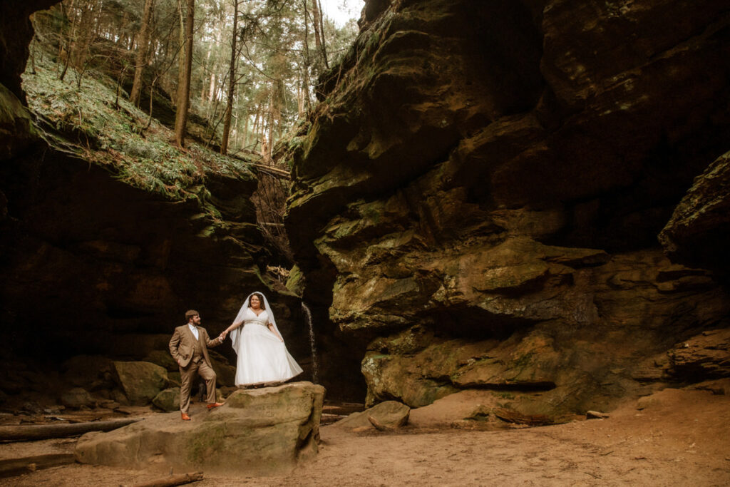 Sarah and Gabe wanted a simple, wedding in nature, so they eloped in Ohio's beautiful Hocking Hills. The rainy spring day made it even more romantic as they said their vows under Ash Cave's huge overhang, the light rain a perfect soundtrack. They then visited Conkles Hollow, where the misty cliffs and green spring growth created a magical scene. Despite the rain, they were so happy, and their elopement was exactly what they dreamed of: a loving celebration in the stunning Hocking Hills.