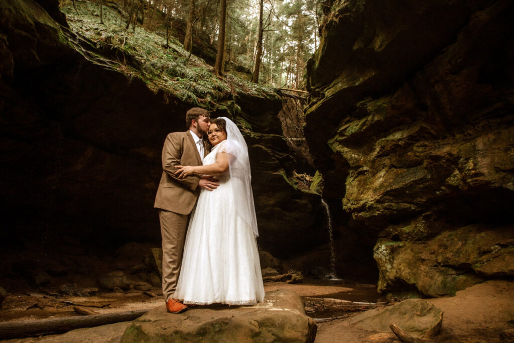 Sarah and Gabe wanted a simple, wedding in nature, so they eloped in Ohio's beautiful Hocking Hills. The rainy spring day made it even more romantic as they said their vows under Ash Cave's huge overhang, the light rain a perfect soundtrack. They then visited Conkles Hollow, where the misty cliffs and green spring growth created a magical scene. Despite the rain, they were so happy, and their elopement was exactly what they dreamed of: a loving celebration in the stunning Hocking Hills.