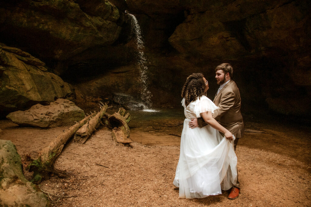 Sarah and Gabe wanted a simple, wedding in nature, so they eloped in Ohio's beautiful Hocking Hills. The rainy spring day made it even more romantic as they said their vows under Ash Cave's huge overhang, the light rain a perfect soundtrack. They then visited Conkles Hollow, where the misty cliffs and green spring growth created a magical scene. Despite the rain, they were so happy, and their elopement was exactly what they dreamed of: a loving celebration in the stunning Hocking Hills.