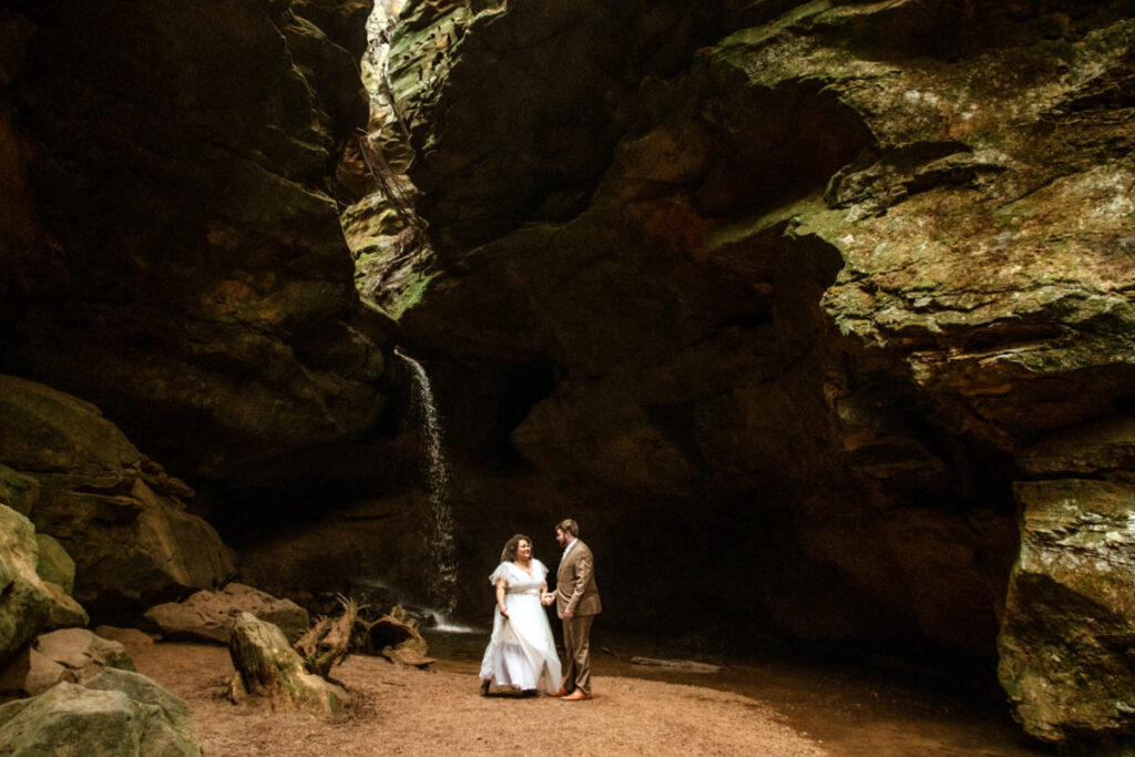 Sarah and Gabe wanted a simple, wedding in nature, so they eloped in Ohio's beautiful Hocking Hills. The rainy spring day made it even more romantic as they said their vows under Ash Cave's huge overhang, the light rain a perfect soundtrack. They then visited Conkles Hollow, where the misty cliffs and green spring growth created a magical scene. Despite the rain, they were so happy, and their elopement was exactly what they dreamed of: a loving celebration in the stunning Hocking Hills.