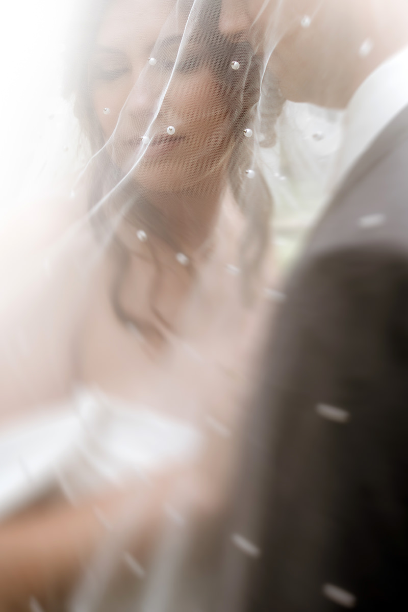 "An artistic, out-of-focus capture of a couple sharing an intimate moment under a wedding veil, highlighting the soulful and authentic style of Hocking Hills elopement photographer Elizabeth Nihiser.