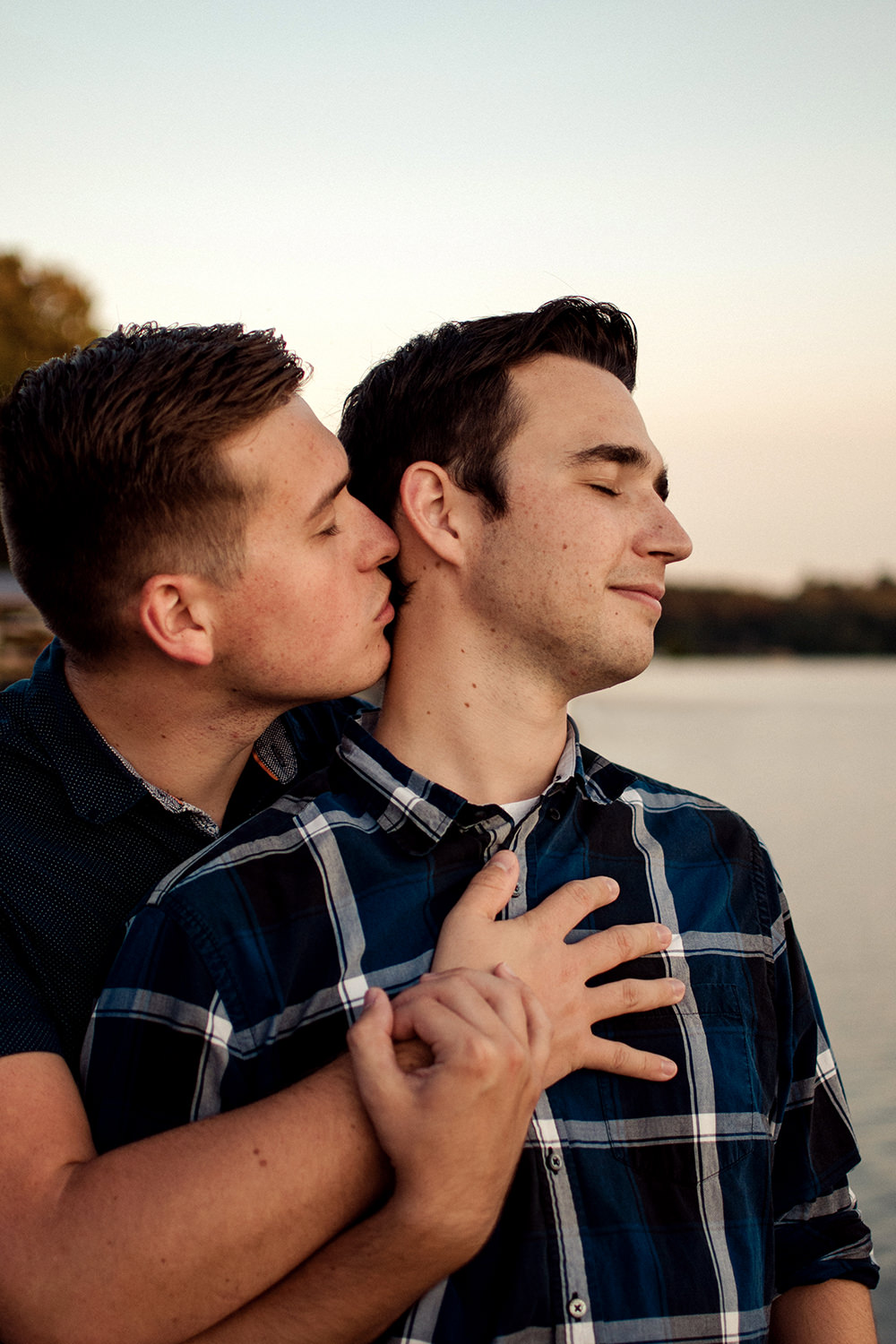 "Intimate sunset golden hour engagement photo of a gay couple embracing at Lake Logan in Hocking Hills, Ohio.