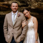Elopement couple smiling at the camera in front of Upper Falls at Old Man’s Cave in Hocking Hills.