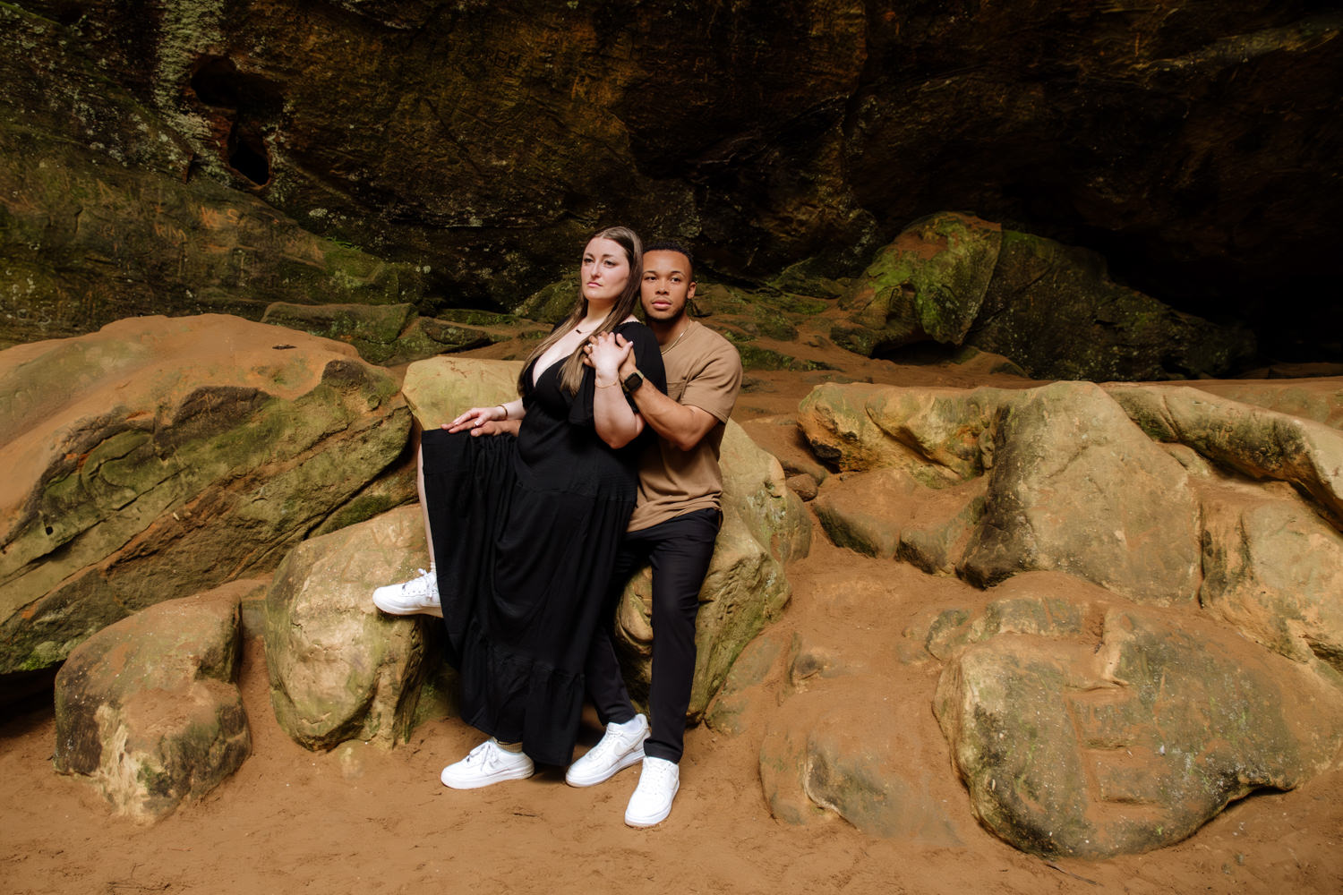 An artistic portrait and pose of a woman and man sitting on rocks in Ash Cave.