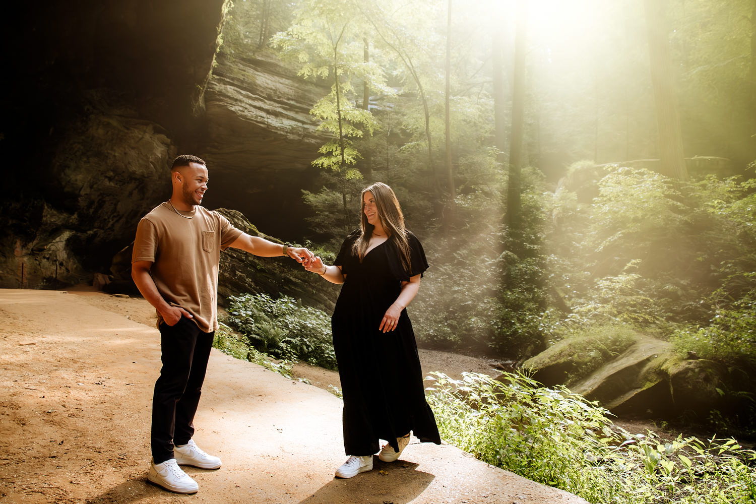 A man and woman dance in Ash Cave as rays of light fall behind them.