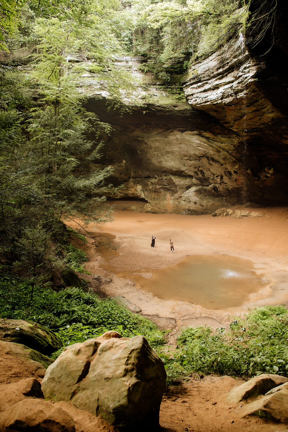 A wide view of the waterfall and pool at Ash Cave in the Hocking Hills. The people by the pool look like ants.