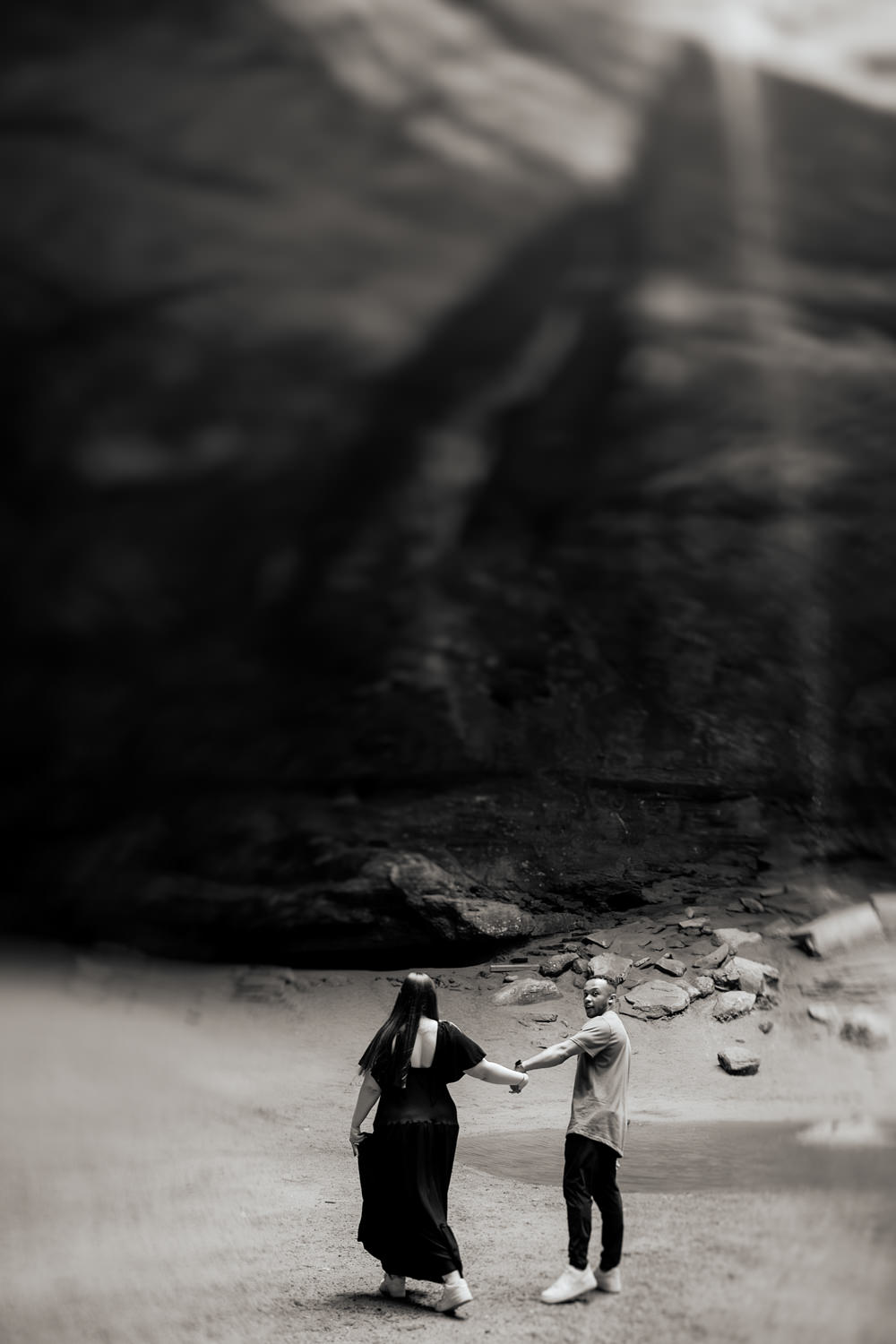A wide scale black and white photo of a couple dancing by the waterfall at Ash Cave.