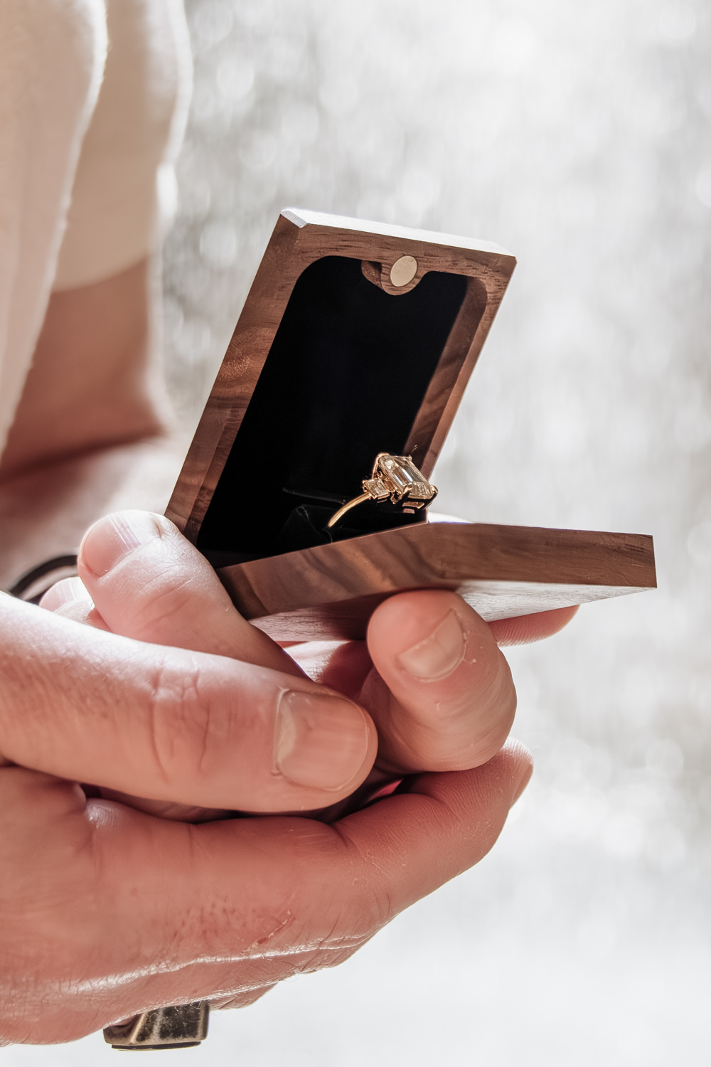A man holds an engagement ring and box in his hands.