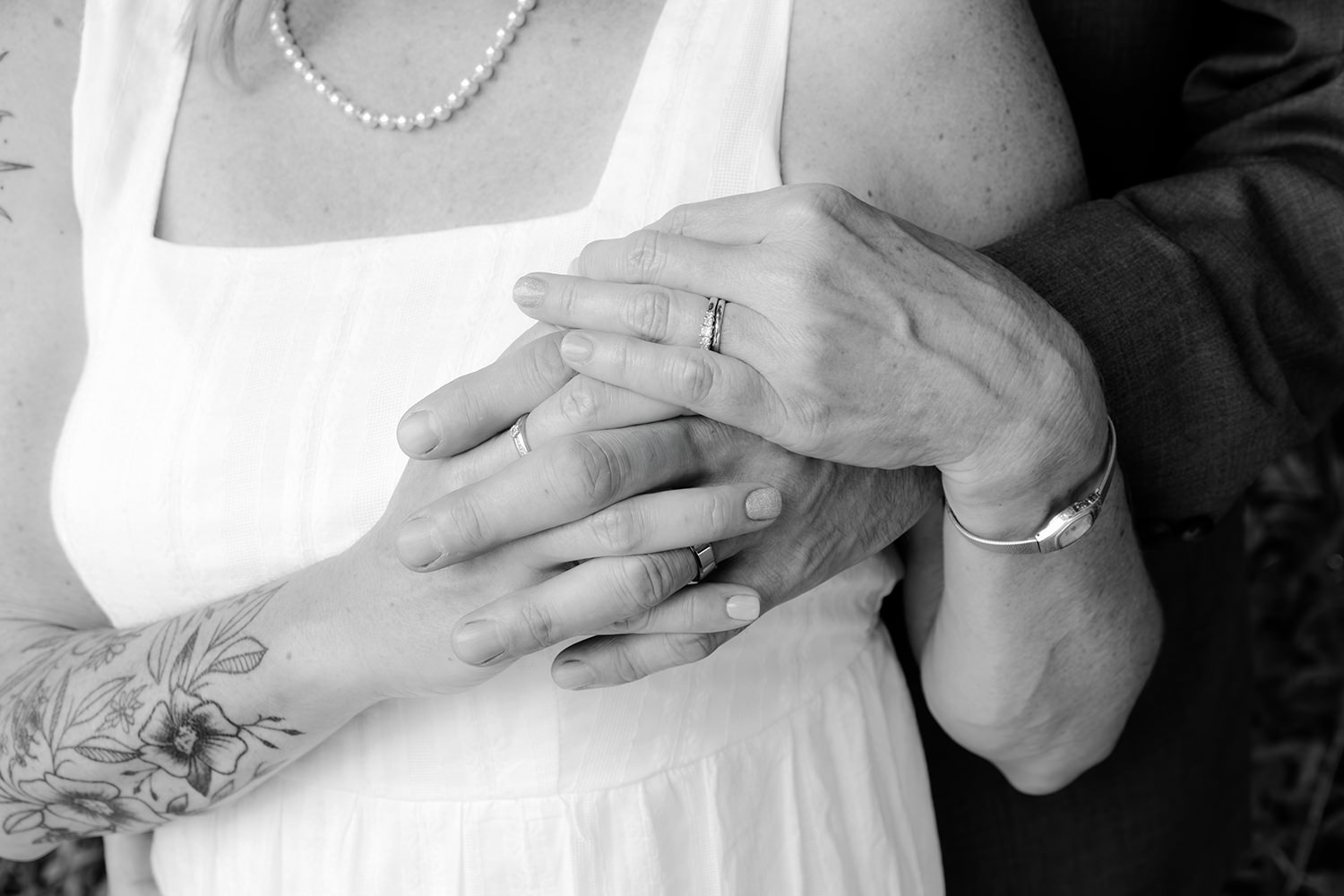 A black and white vintage style photo of a couple's hands embracing and overlapping. The photo was taken on their 25th wedding anniversary.