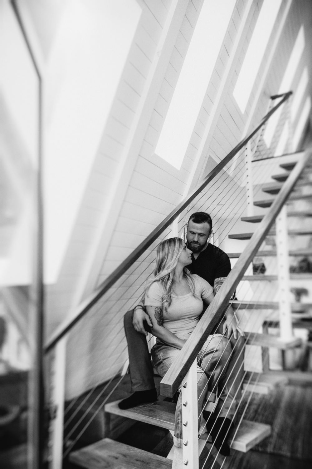 A man and woman sit on the stairs of the Dunlap Hollow A-frame cabin in the Hocking Hills. The photo is in black and white and artistically blurred.