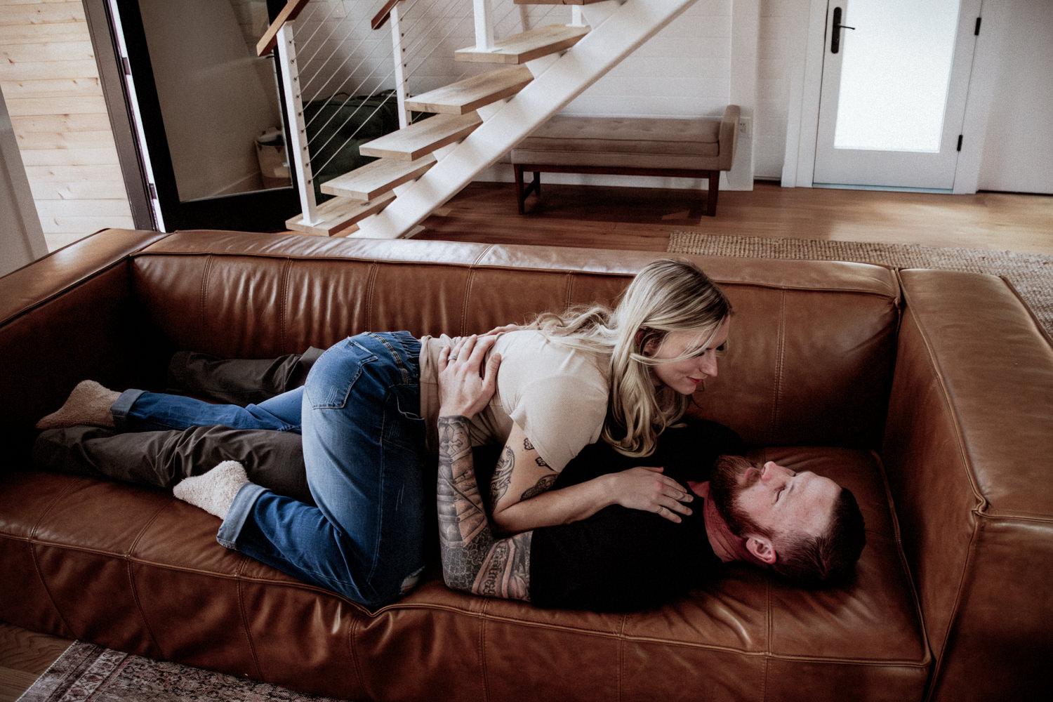 A woman lays on a man who is in turn laying on a couch at Dunlap Hollow cabin in the Hocking Hills.