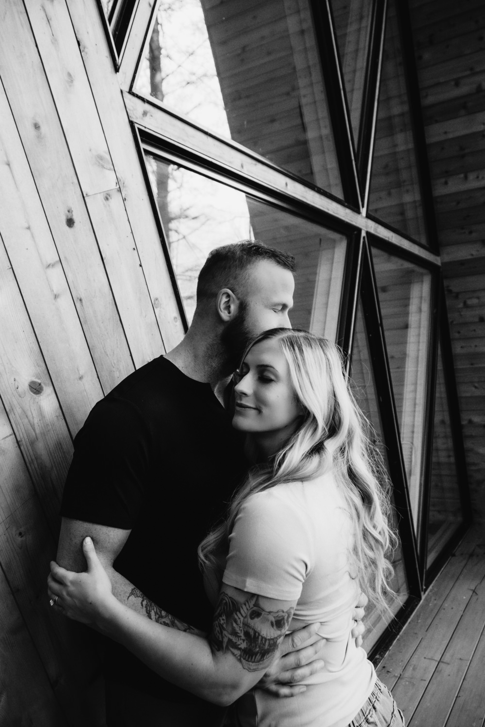 A woman and man pose on the balcony of an A-frame cabin in Ohio for their anniversary portraits. They traveled from North Dakota for their photo session.
