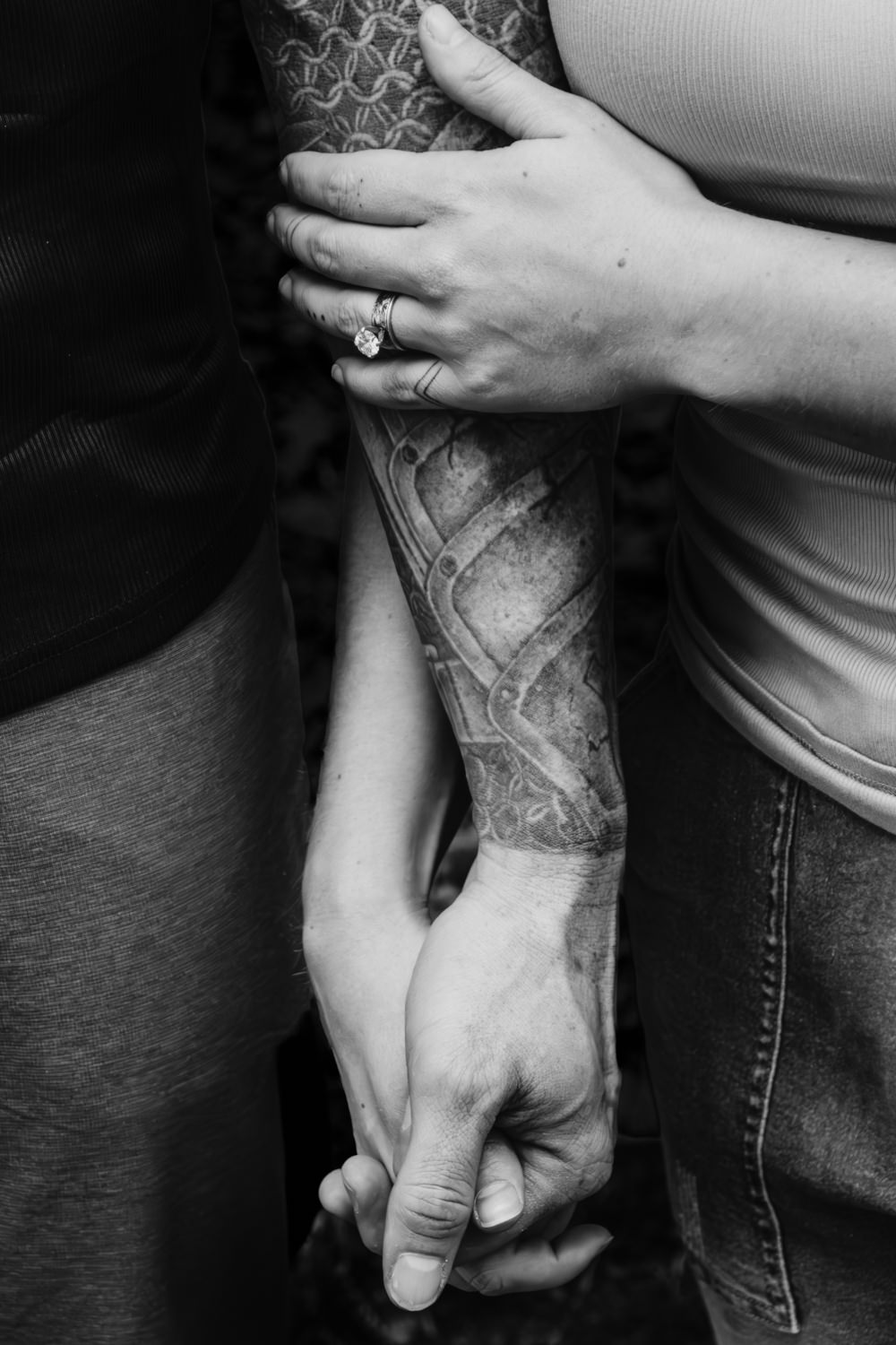 A woman with a wedding ring holds the arm of a tattooed man, her husband of 5 years. They are holding hands and celebrating their anniversary.