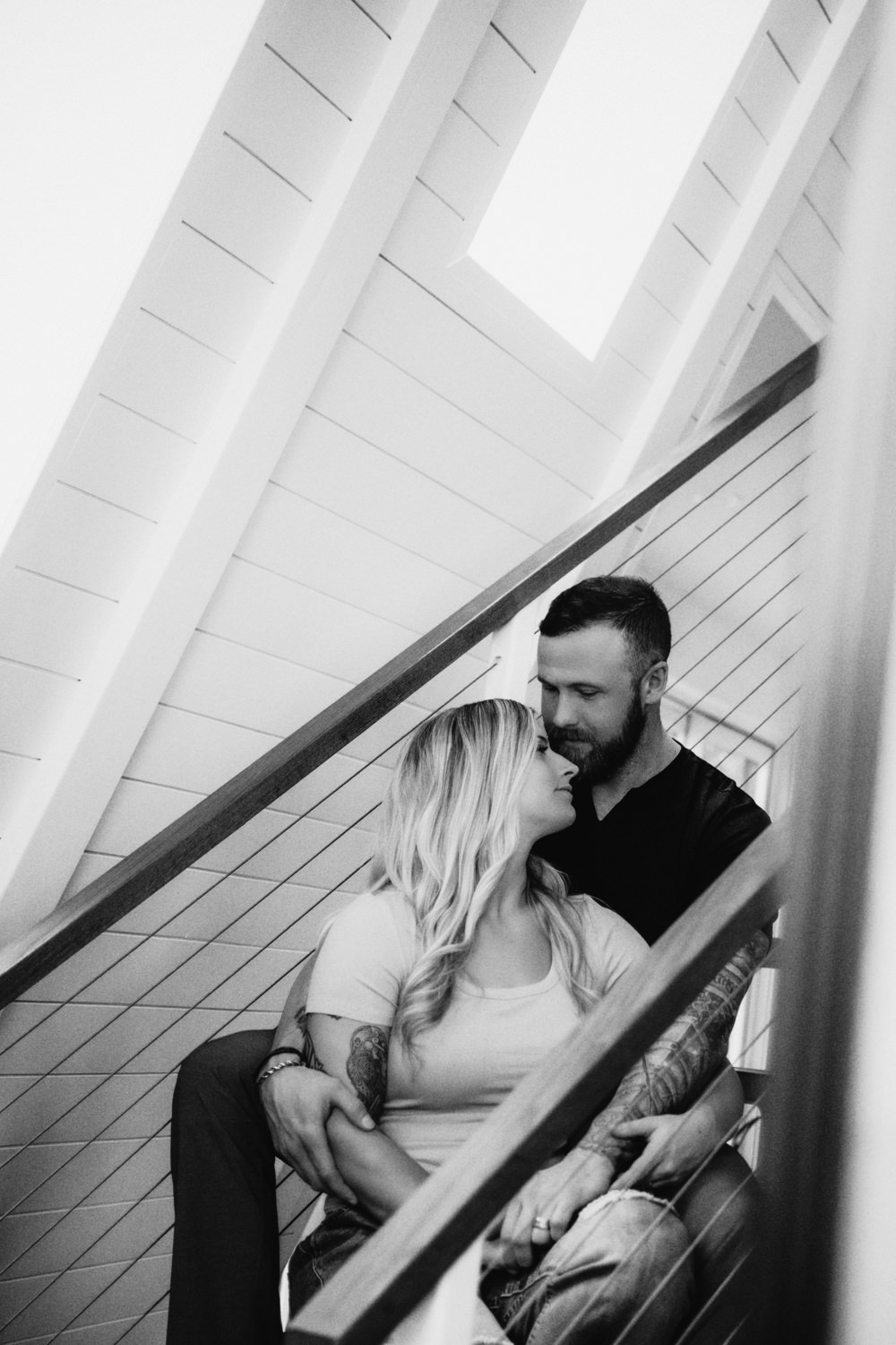A man and woman sit on the stairs of the Dunlap Hollow A-frame cabin in the Hocking Hills. The photo is in black and white.