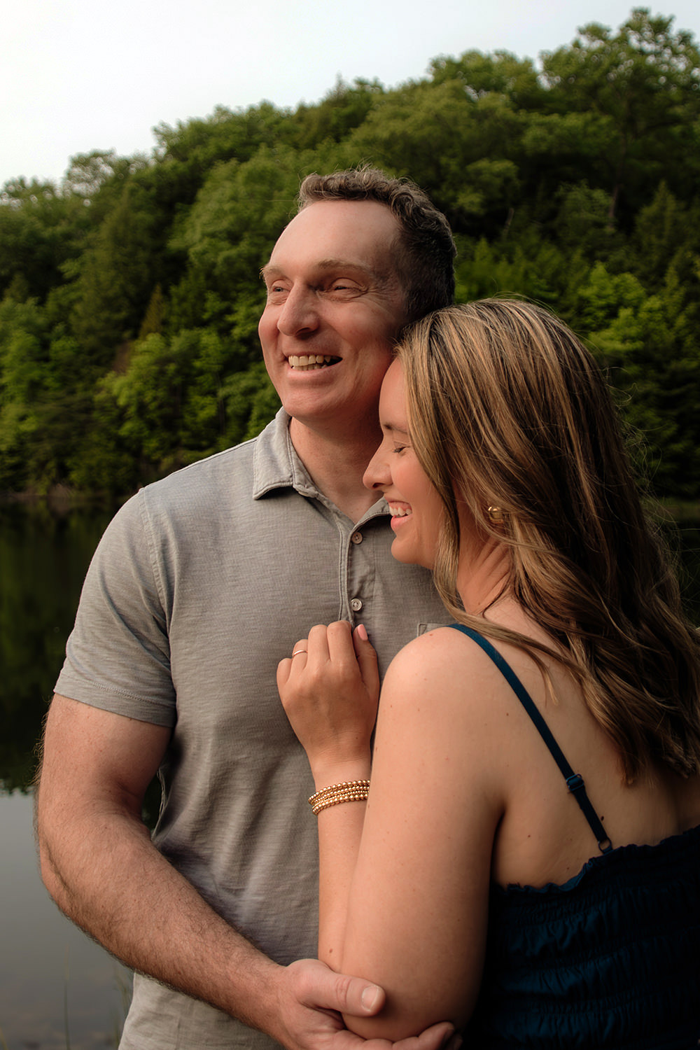 A middle age couple giggles and holds each other closer during their Rose Lake anniversary photo session in the Hocking Hills, Ohio.