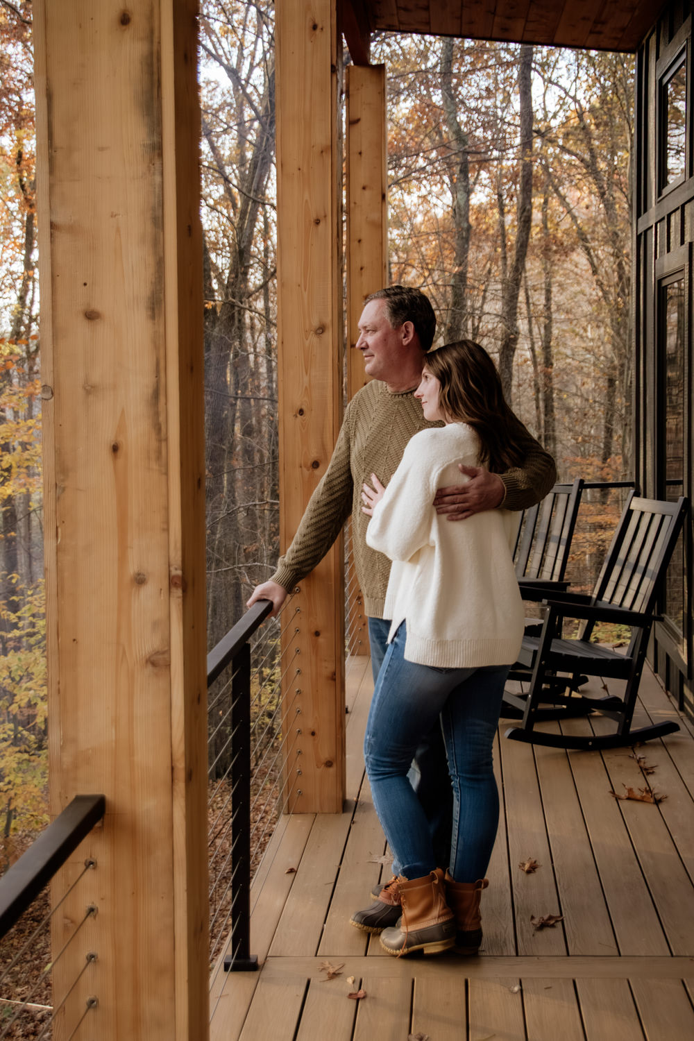 A romantic close-up of Taylor and Jeff sharing a laugh, with the warm golden hour sun creating a beautiful rim light around them against the rustic cabin backdrop.