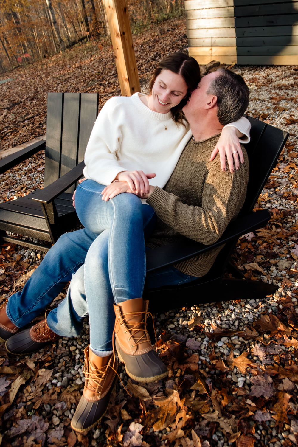 A scenic shot of Taylor and Jeff sitting on the edge of the cabin’s deck, looking out into the dense, sunlit woods of Dunlap Ridge during their anniversary session.