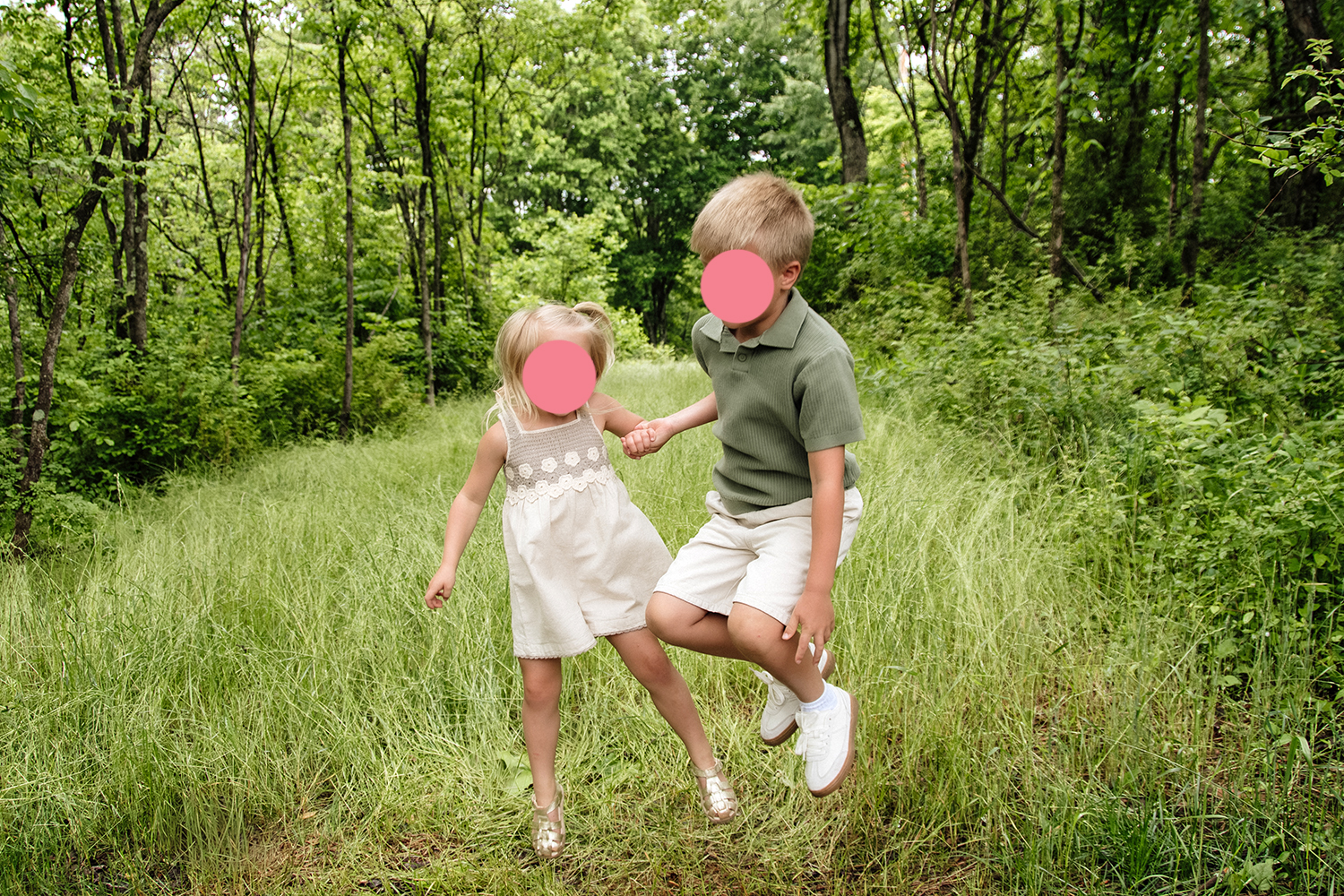 Two siblings hold hands and jump up during an extended family photo session in the Hocking Hills, Ohio.