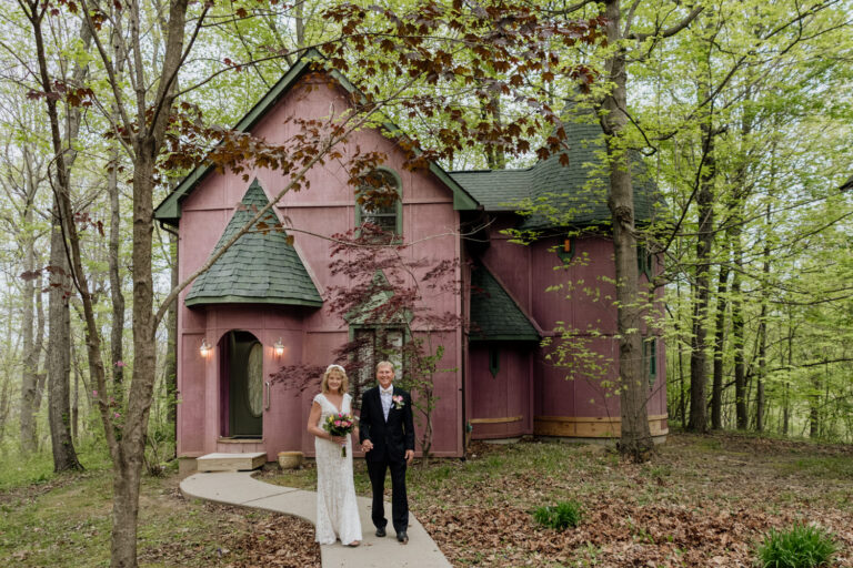 A couple walks out of the pink Silversmith's Lodge at Ravenwood Castle on their way to renew their vows on their 35th wedding anniversary.