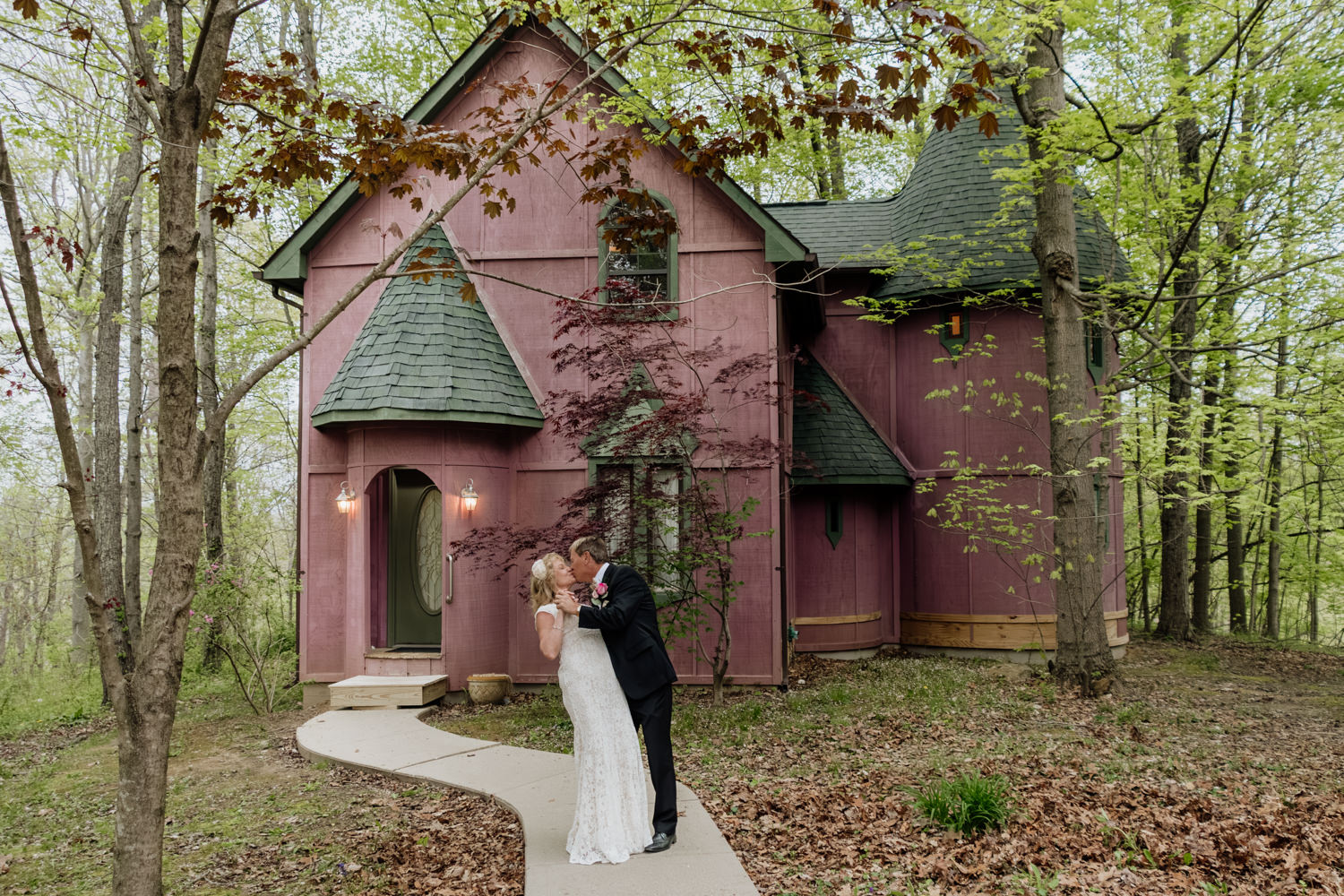 A couple walks out of the pink Silversmith's Lodge at Ravenwood Castle on their way to renew their vows on their 35th wedding anniversary.