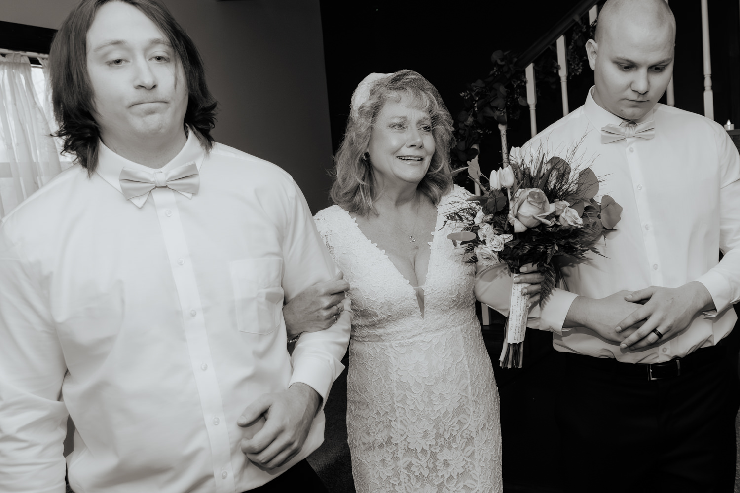 A teary eyed woman links arms with her adult sons as they walk her down the aisle for her 35th anniversary vow renewal.