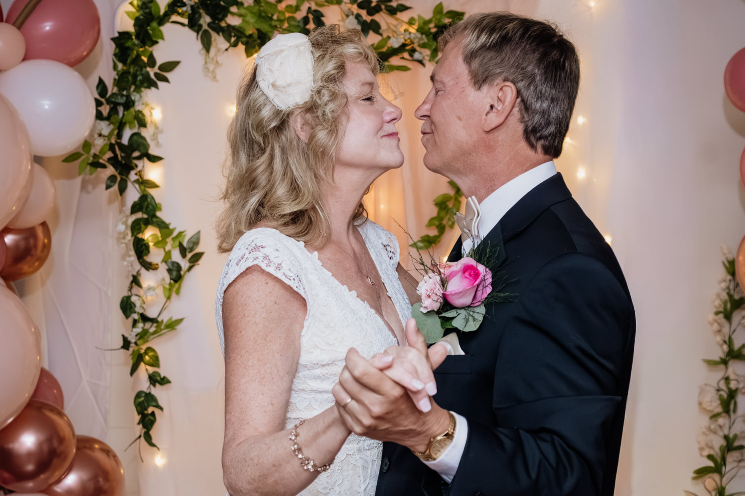 A close up of a man and woman in their 60s slow dancing in front of the altar.