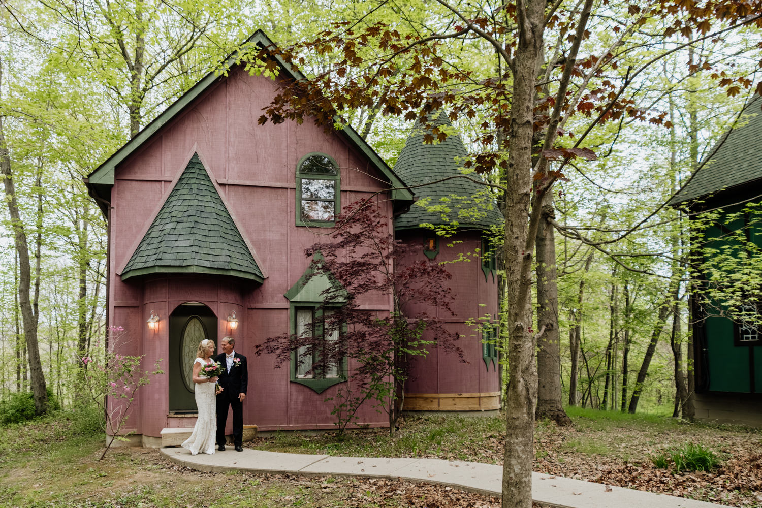 A couple walks out of the pink Silversmith's Lodge at Ravenwood Castle on their way to renew their vows on their 35th wedding anniversary.