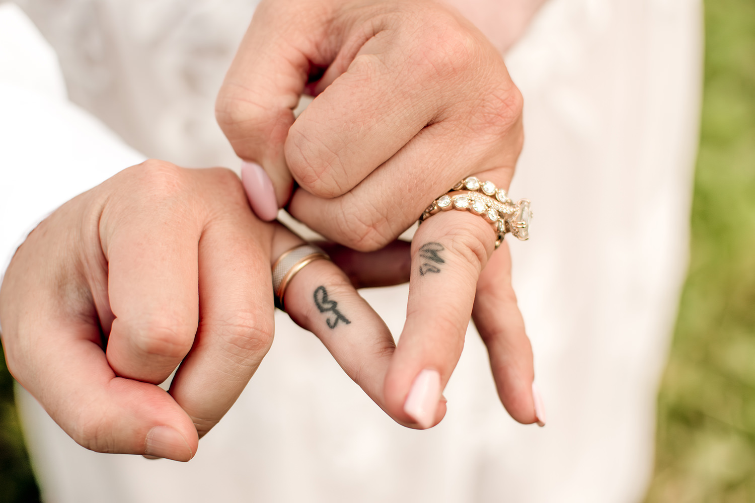 Two brides hold up finger tattoos.