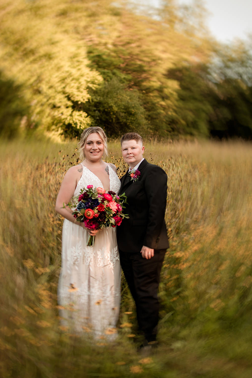 A queer couple stands in a vibrant yellow wildflower field in the Hocking Hills.