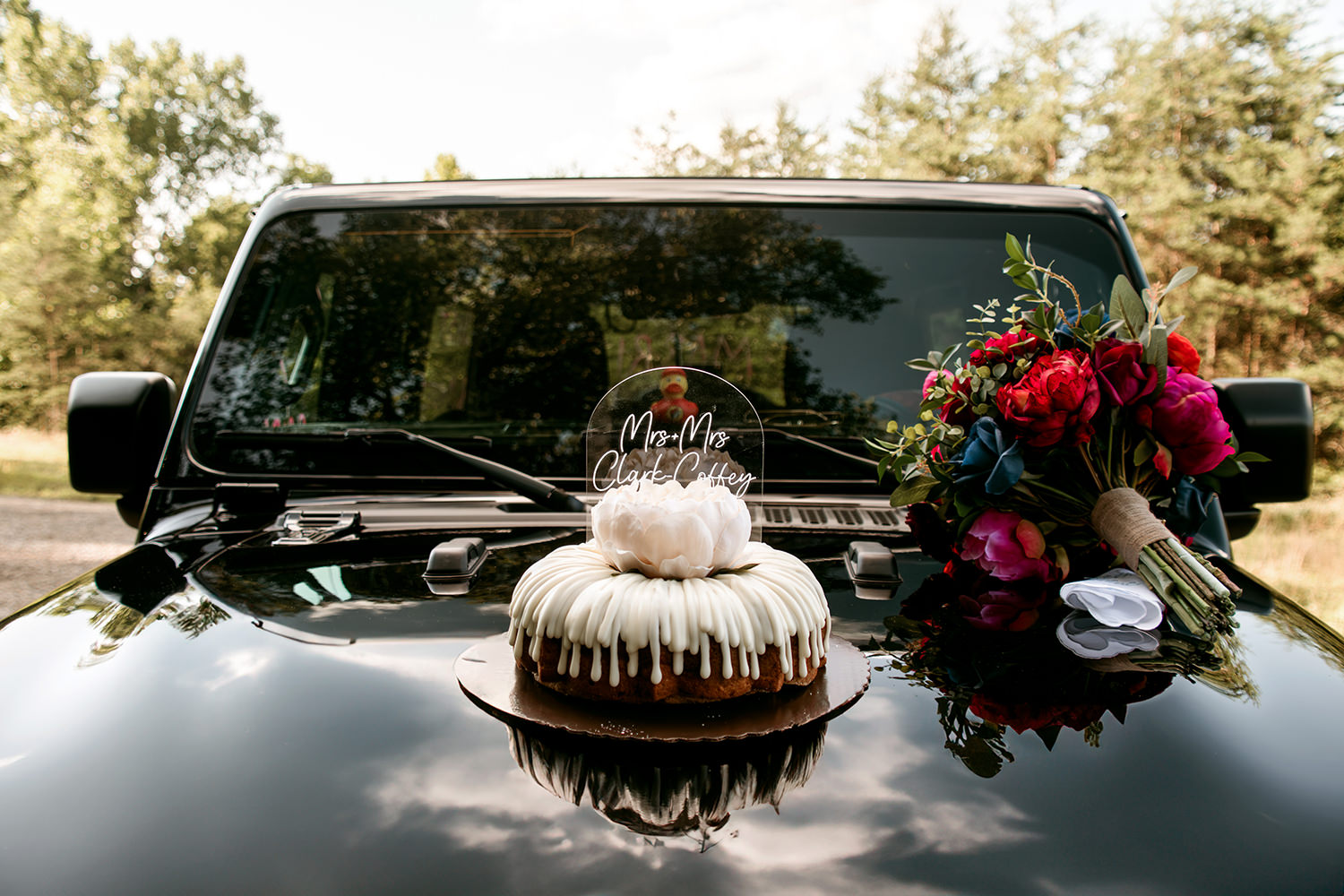 Nothing Bundt Cakes sits on a Jeep hood with a bouquet during a vow renewal.