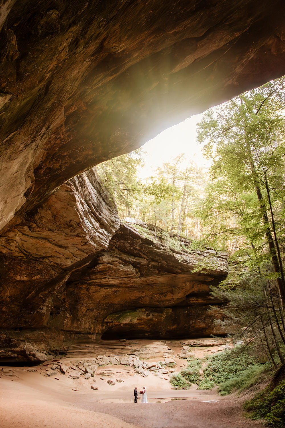 Epic wide shot of Ash Cave with a tiny couple by the water pool.
