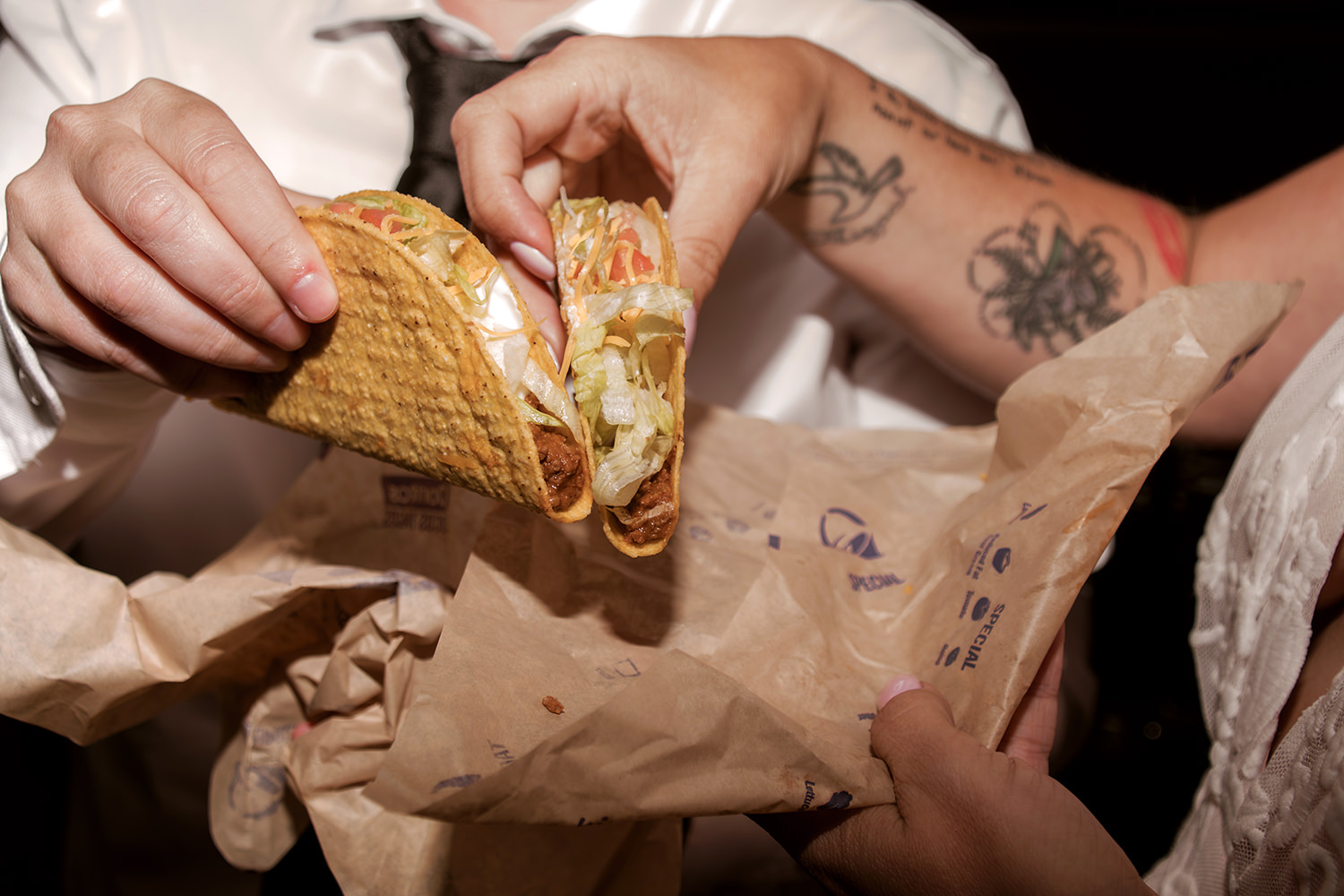 Two brides unwrap tacos from their Taco Bell wrappers.