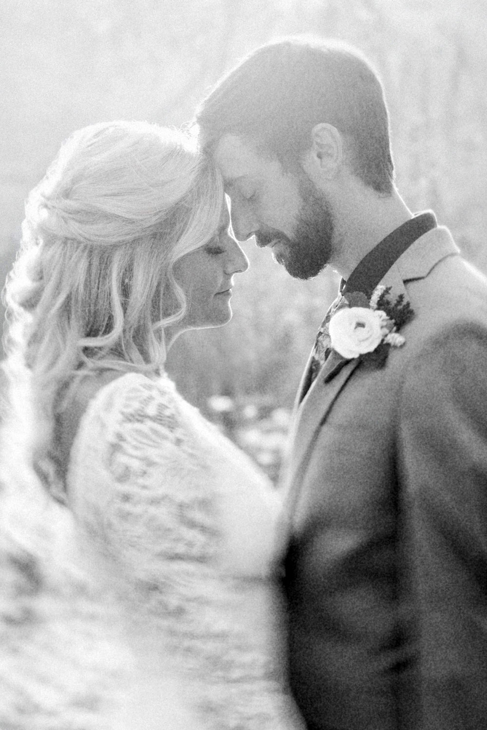 A vintage style black and white photograph of a couple with their foreheads pressed together on their wedding day at Ravenwood Castle in Hocking Hills, Ohio. The lighting is ethereal and soft.