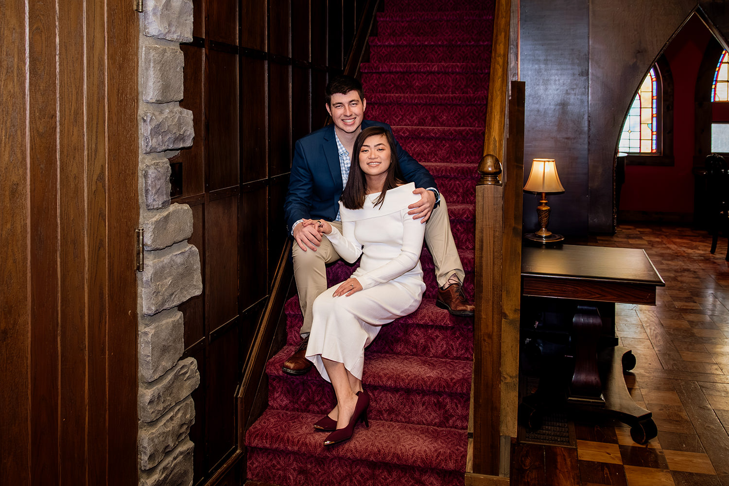 A couple sits and smiles on the stairs inside Ravenwood Castle dining hall in Ohio.
