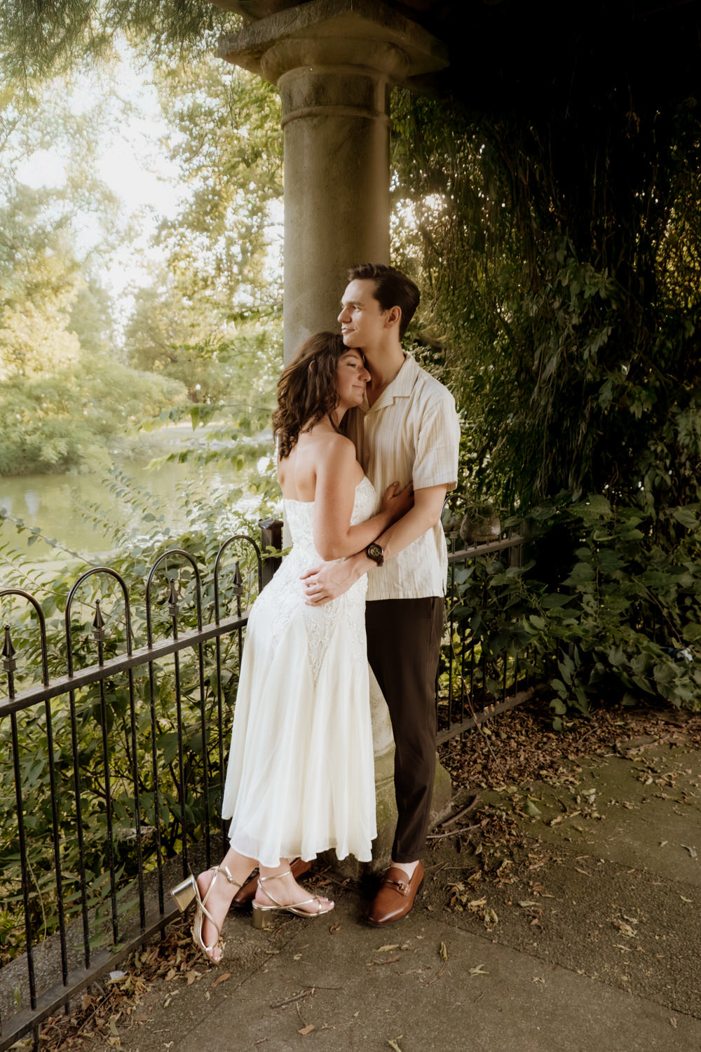 A man and woman have a sweet and romantic moment as they cuddle under an arbor in Schiller Park Columbus.