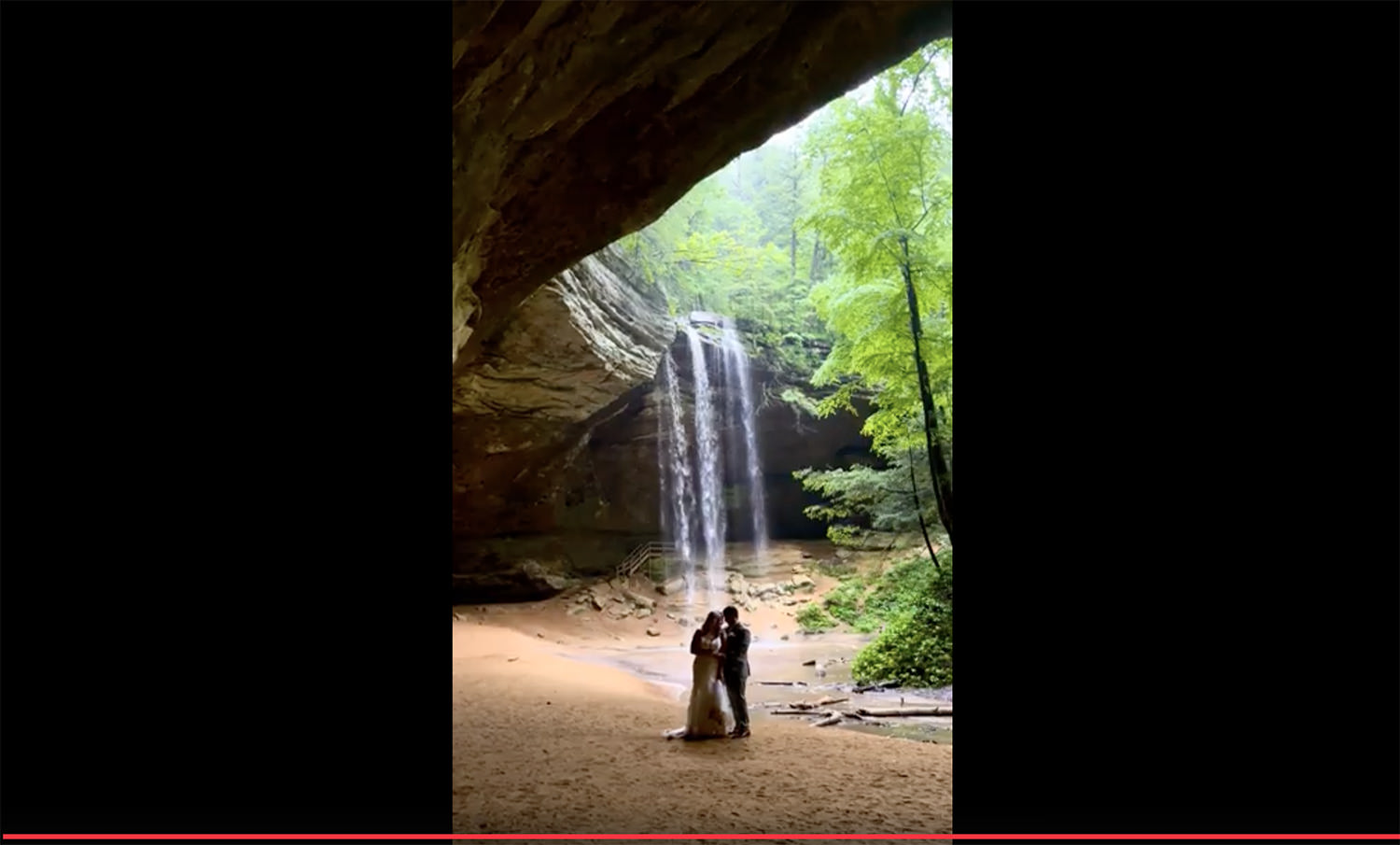 Screenshot of a video clip of an elopement couple in the rain at Ash Cave.
