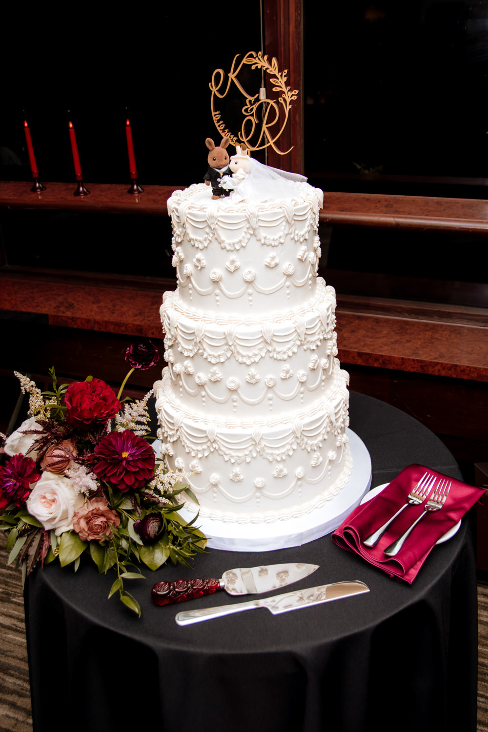 A multi-tiered vintage wedding cake featuring intricate Lambeth piping, white buttercream frosting, and retro styling at a reception.