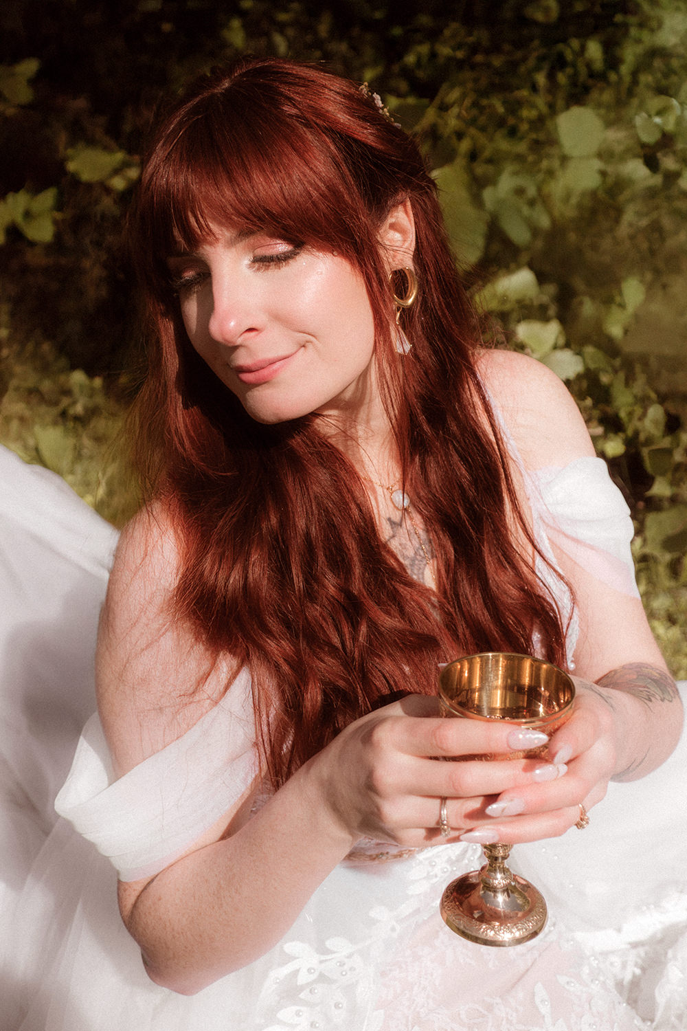 A woman with red hair leans away and holds a gold goblet during her elopement day in Hocking Hills. 