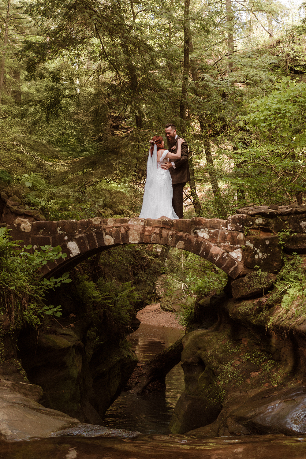 An elopement couple dance on a stone bridge at Old Man's Cave in Hocking Hills.  It looks like a movie scene of Rivendell in Lord of the Rings.