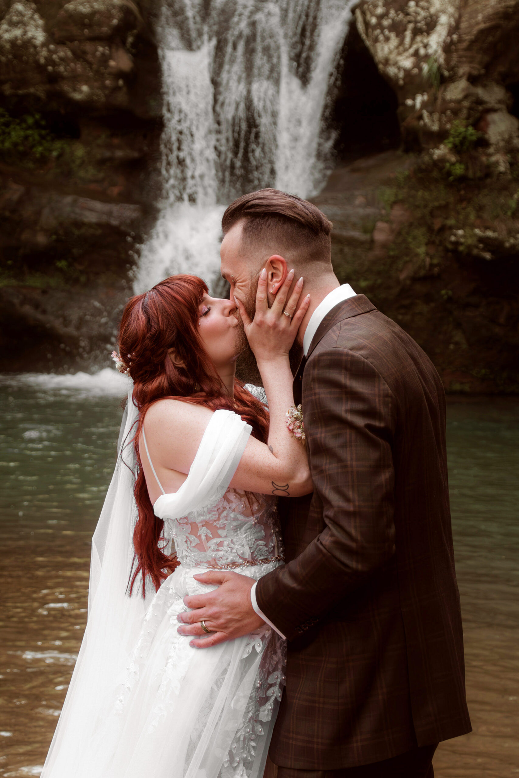 A man and woman kiss in front of a waterfall in Hocking Hills State Park.