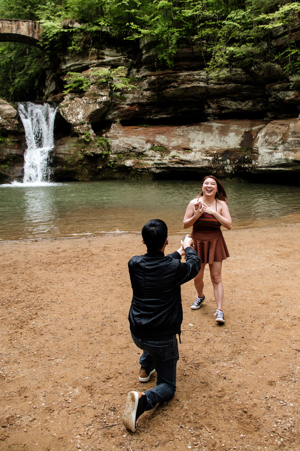 A man with his back to the camera proposes to his girlfriend at Upper Falls in Hocking Hills.
