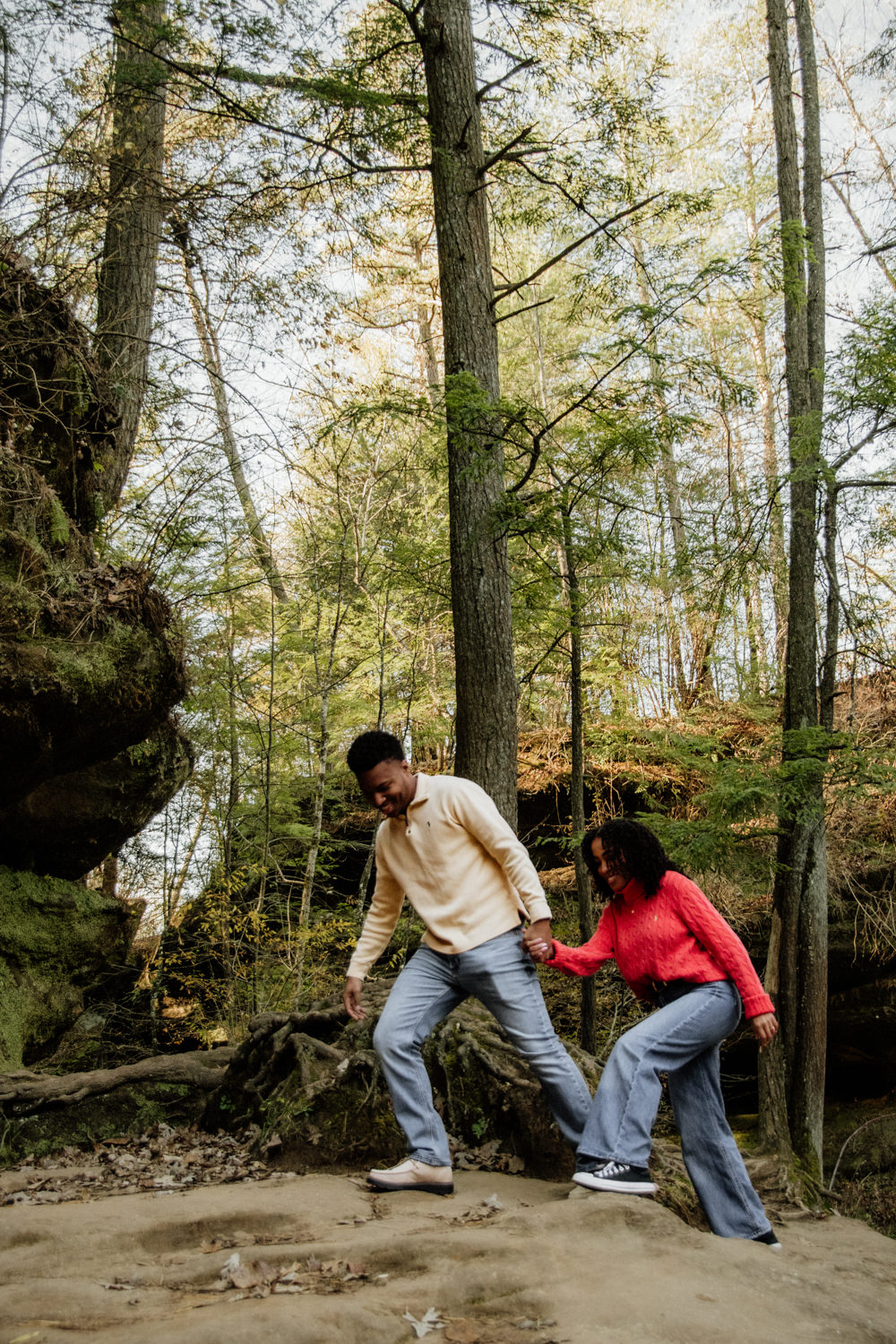 A black couple holds hands and hikes up a sandstone cliff at Old Man's Cave in the Hocking Hills.