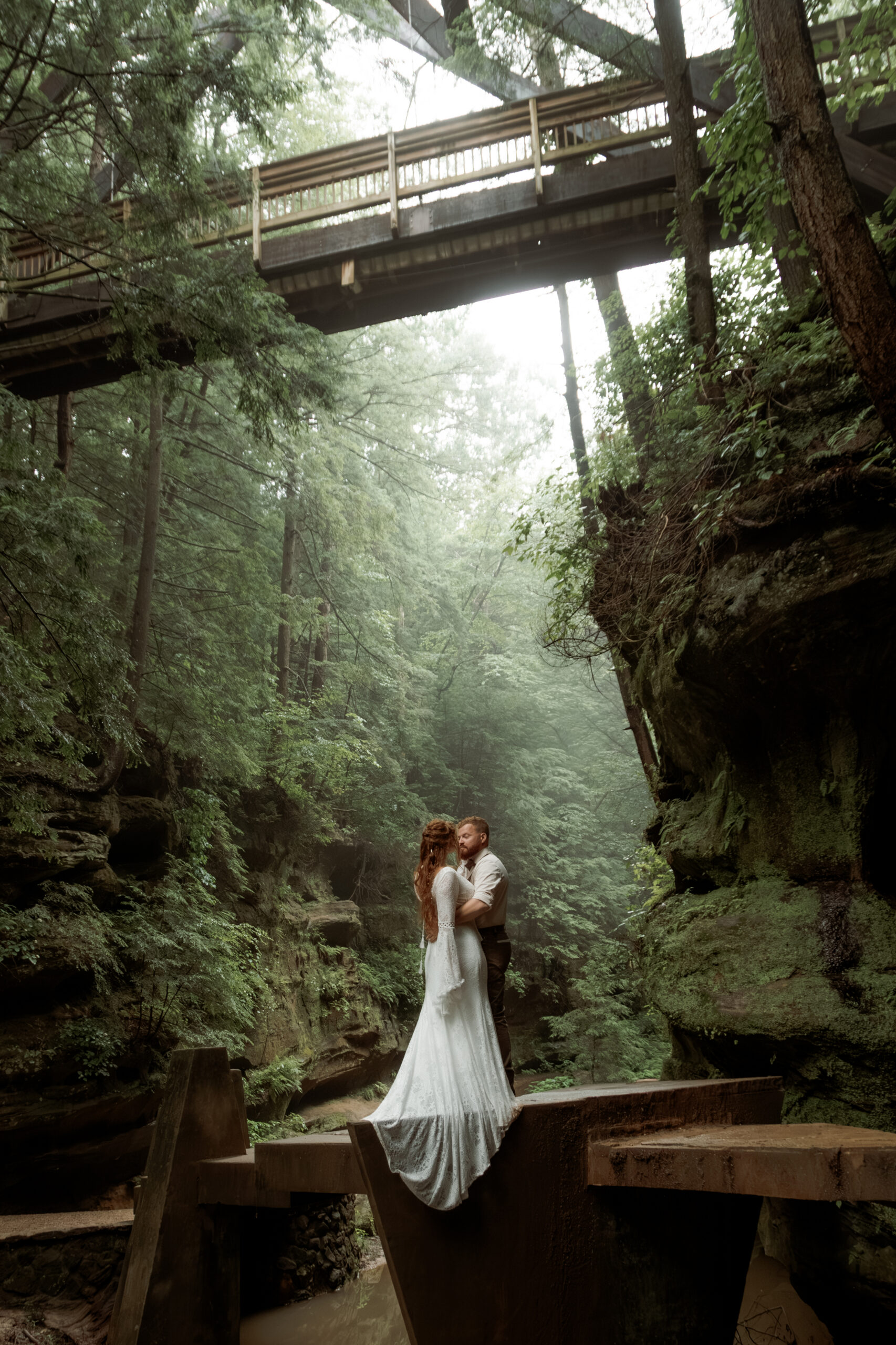 Hocking Hills elopement couple standing on a misty bridge in Old Man's Cave gorge.