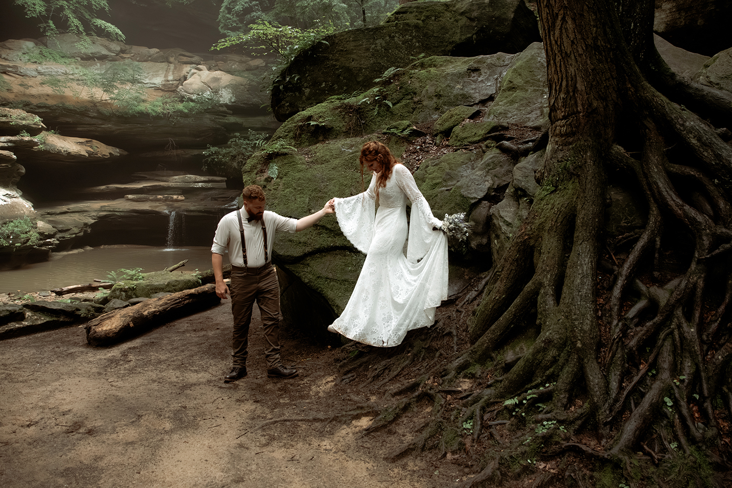 Moody portrait of a couple walking in a deep green forest, their red hair and brown and cream attire perfectly complementing the natural landscape.