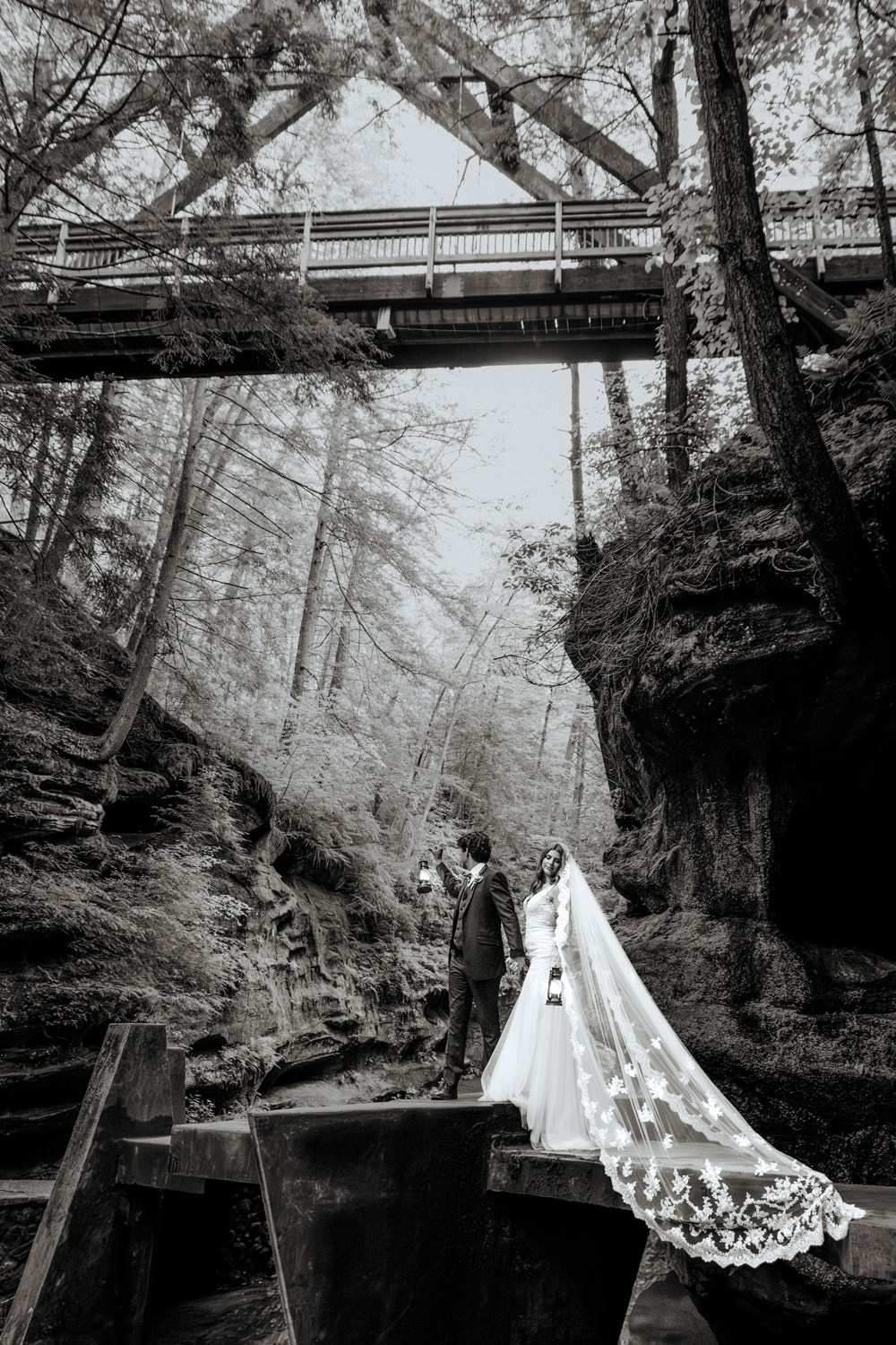 An elopement could stands under the A-frame bridge at Old Man's Cave gorge.  They carry lanterns.