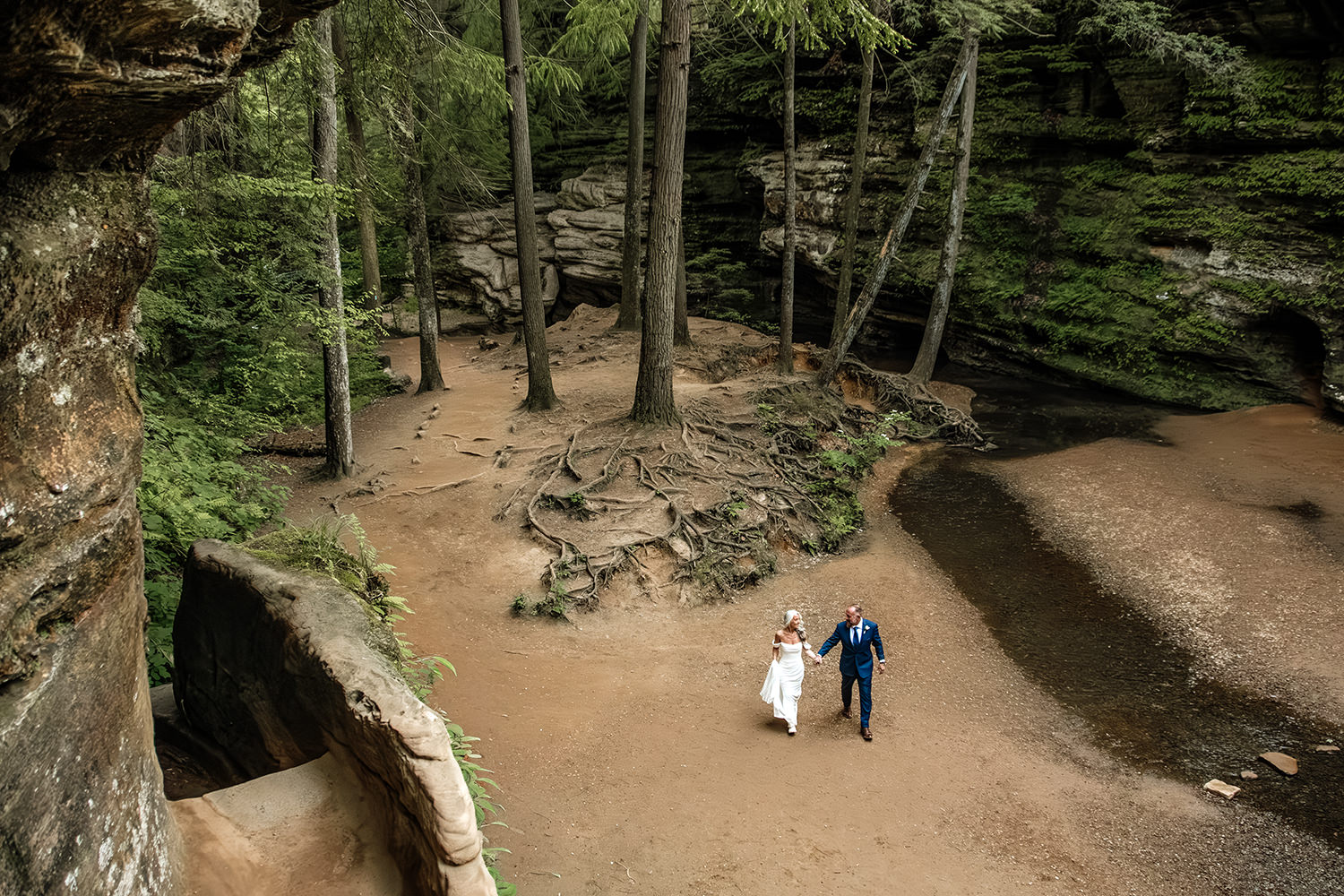 A wide angle overhead perspective of an elopement couple walking through the gorge at Old Man's Cave on their wedding day.