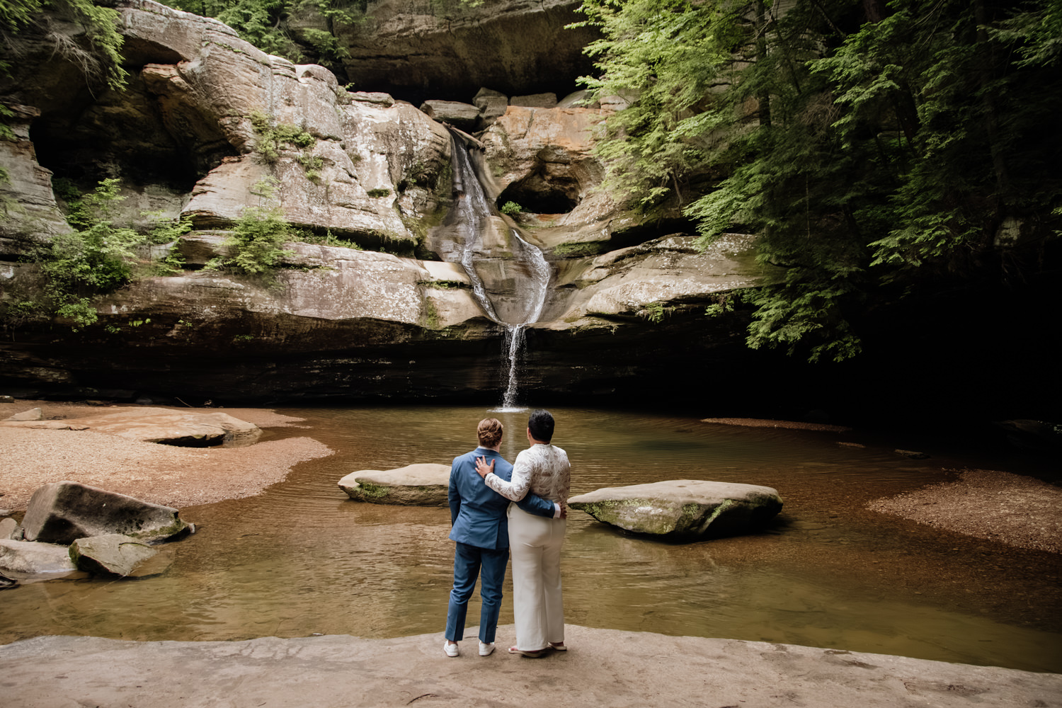 Editorial portrait of a married couple standing inside a massive recess cave in Hocking Hills State Park.