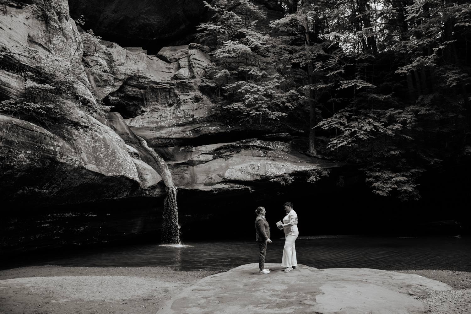 Brides exchanging wedding vows in front of towering hemlocks and massive sandstone cliffs at Cedar Falls.