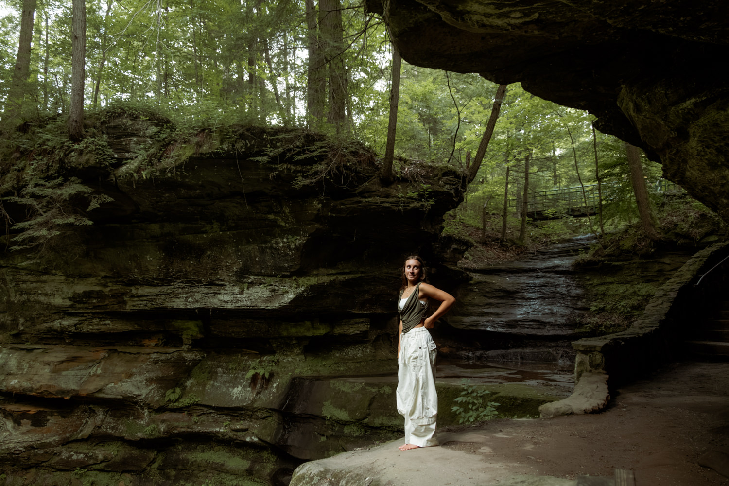 Candid moment of a high school senior exploring a mossy sandstone cliff in Ohio