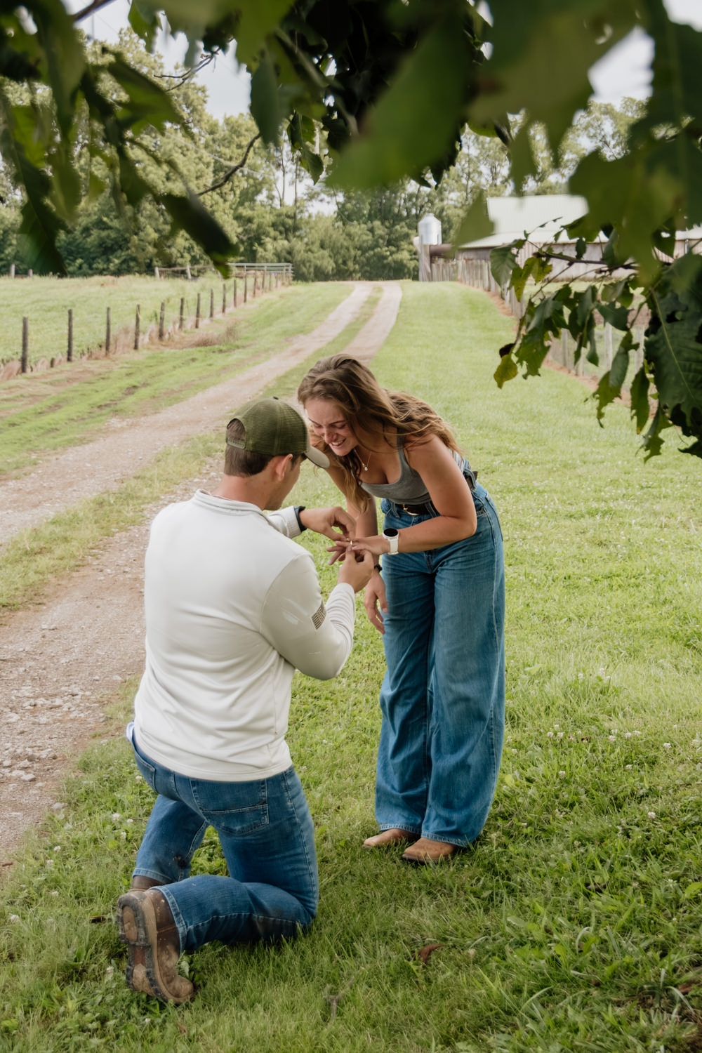 Man kneeling on one knee under a shaded tree proposing to a woman at Spotted Horse Ranch.